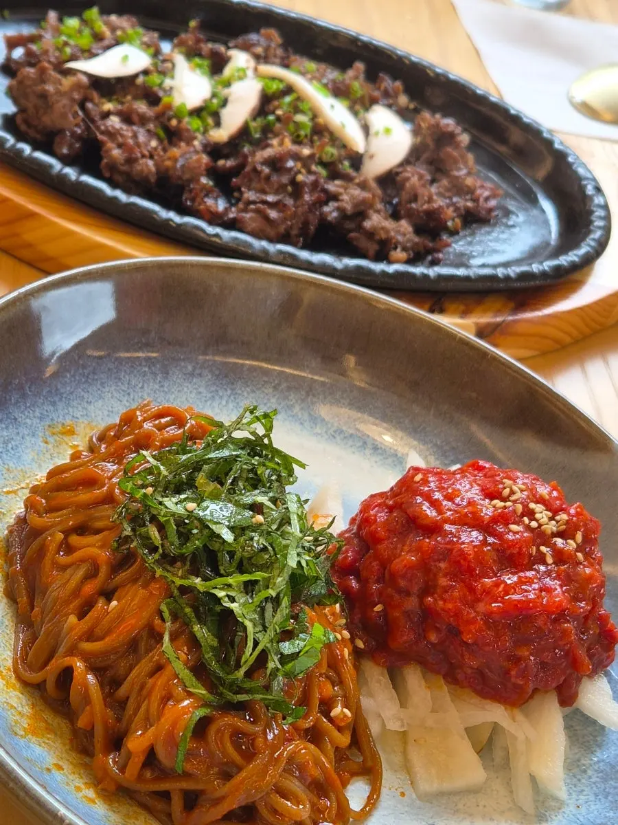 A chopstick-full of yukhoe bibim buckwheat noodles mixed with sauce