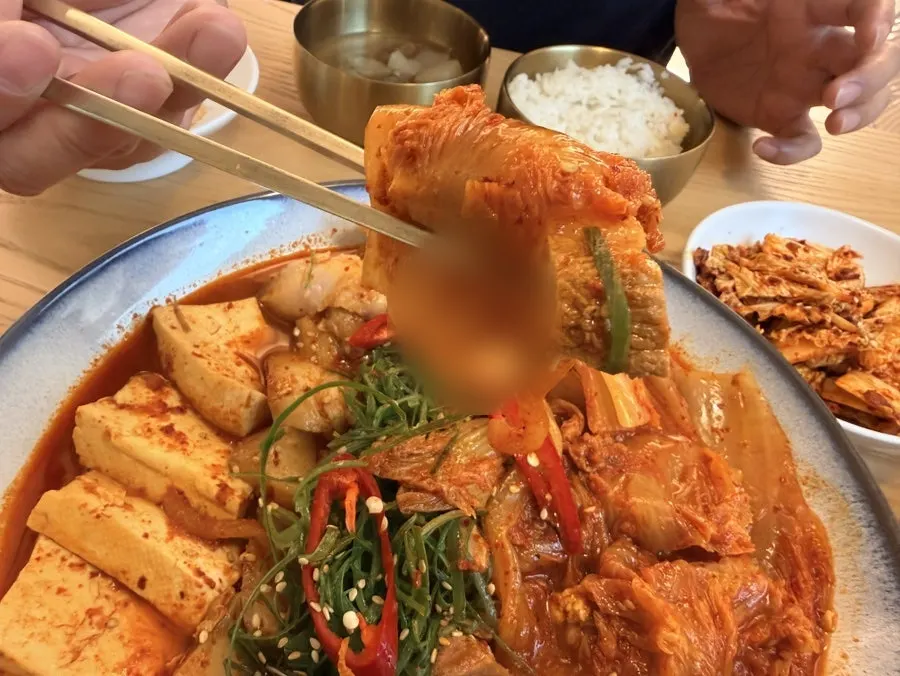 A spoonful of rice topped with kimchi and meat