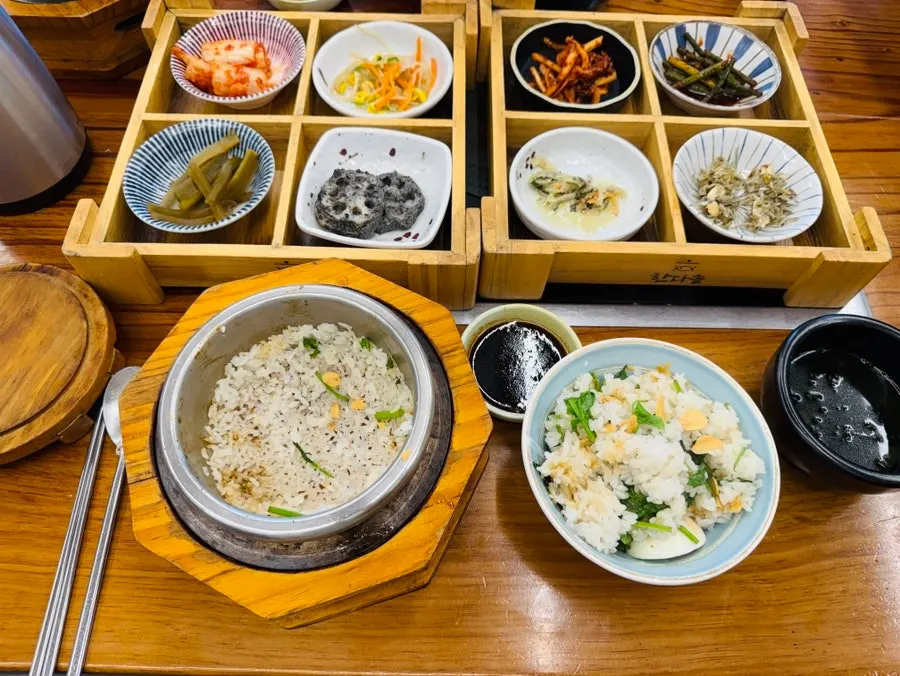 Pot with rice scooped out and water poured in, alongside side dishes