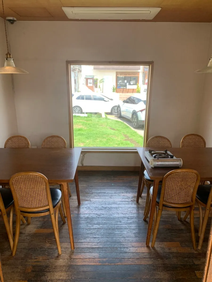 A room with a wide window showing a green view