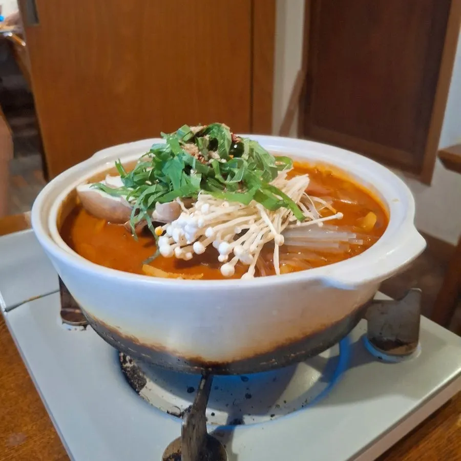 Beef tripe hot pot table setting with mushrooms, glass noodles, and perilla leaves