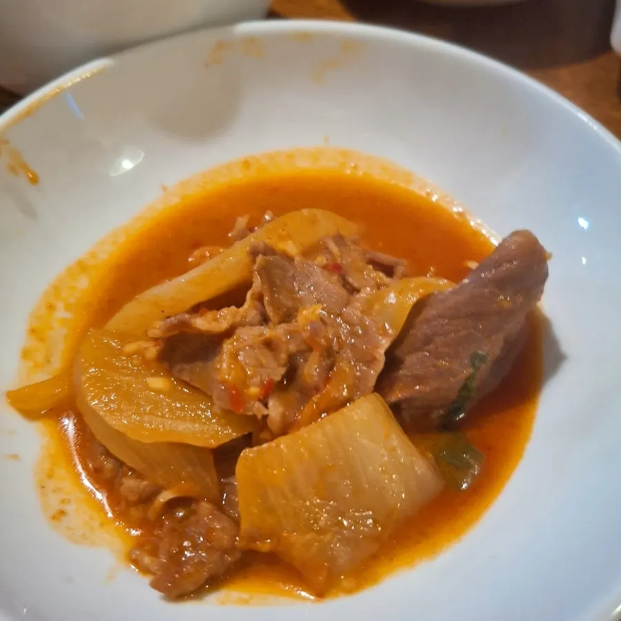 A ladle scooping up beef tripe hot pot broth and tripe
