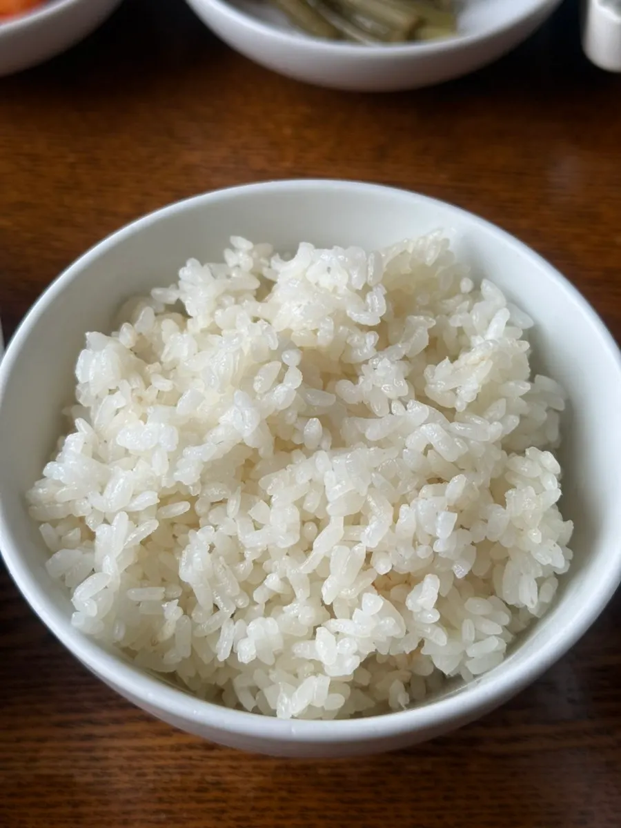 Small plate of seaweed flakes next to a bowl of rice