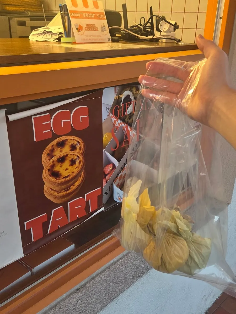 A hand holding a bag of Tareudang fruit mochi