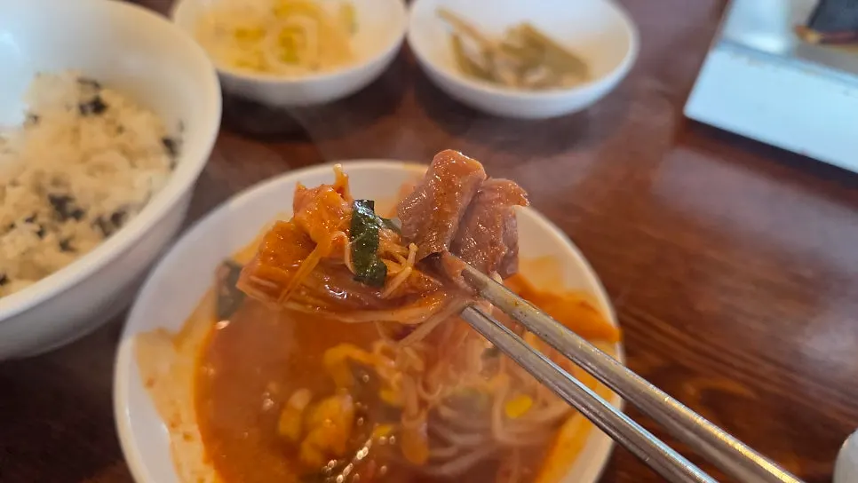 A bowl of hot pot with enoki mushrooms and onion