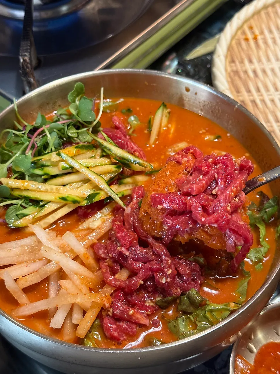Noodles dipped into the yukhoe mulhoe broth