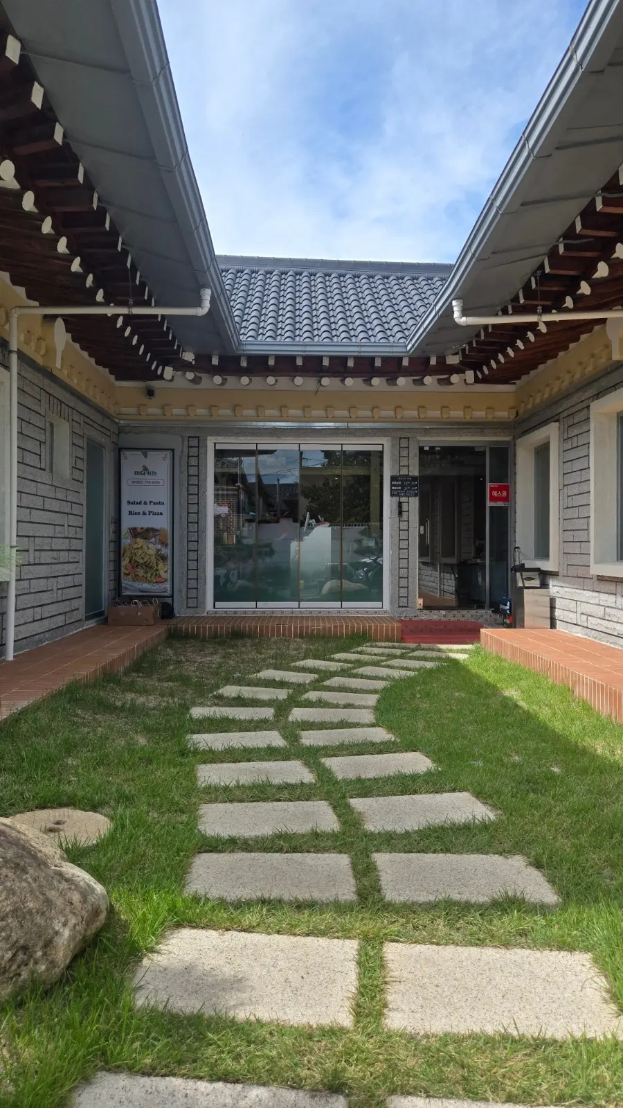Midam Kitchen's exterior with a tiled-roof hanok and lawn