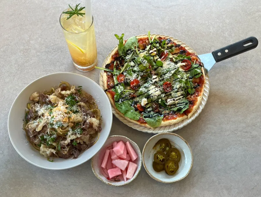 Arugula tomato pizza and beef brisket oil pasta served together