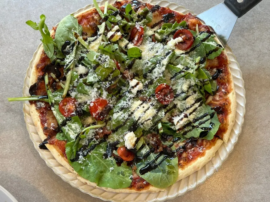 Tomato pizza topped generously with arugula