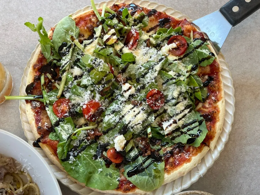 Arugula tomato pizza dusted generously with cheese powder