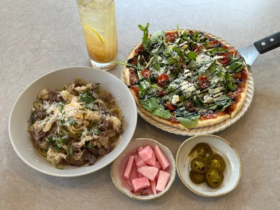 Table with pizza, pasta, pickles, and jalapeños together