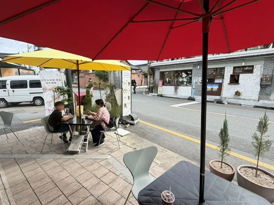 Tables and chairs under parasols in front of the shop