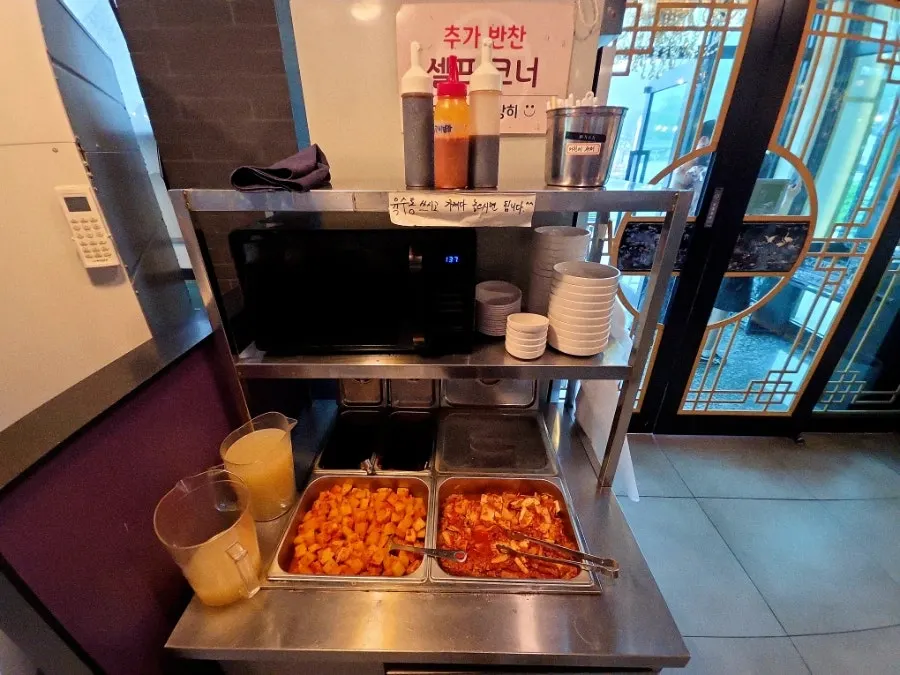 Self-service side dish corner stocked with kkakdugi and kimchi