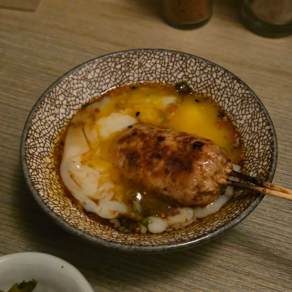 Poached egg sauce broken over tsukune