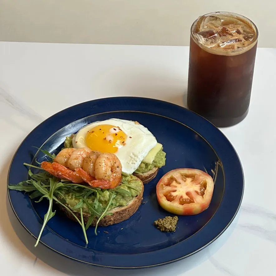Brunch topped with shrimp and a soft-boiled fried egg