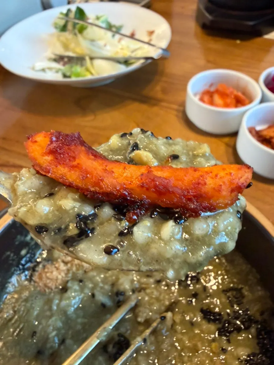 전복죽 위에 더덕구이를 올린 한 숟갈