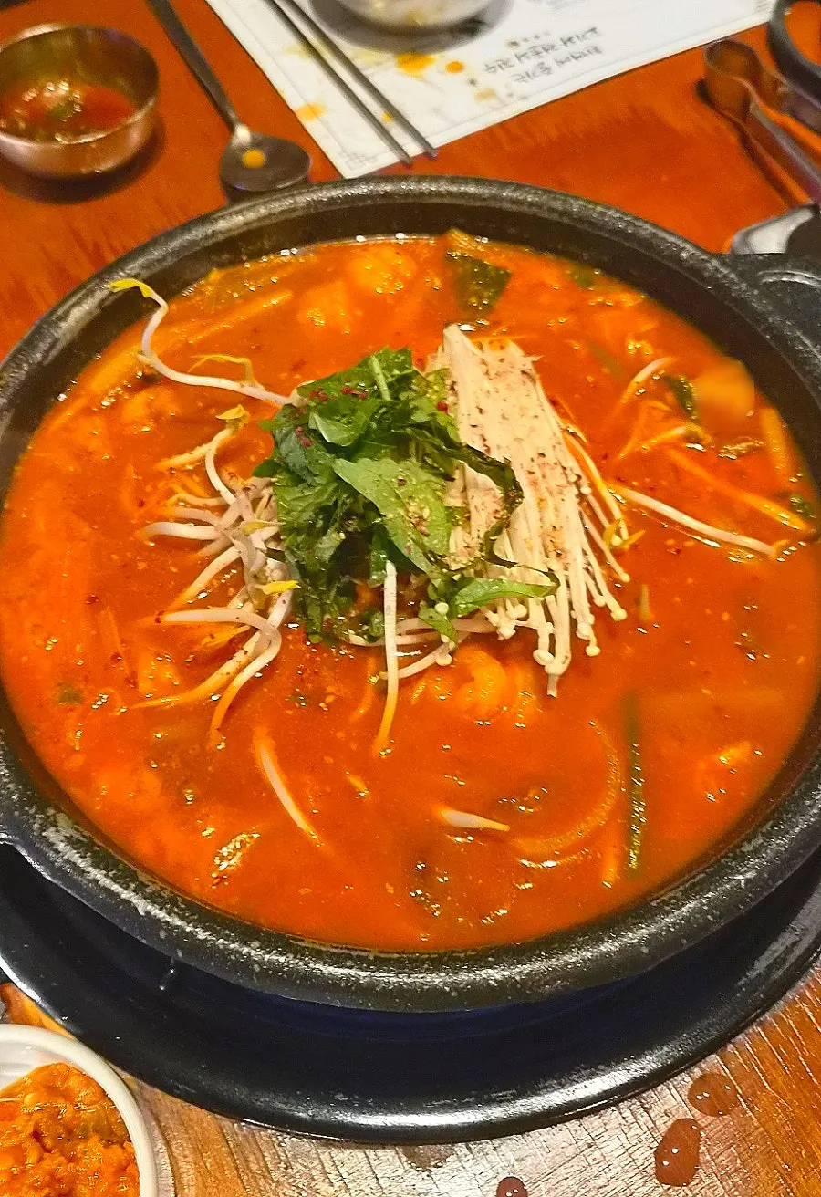 Daechang hot pot topped with enoki mushrooms and perilla leaves