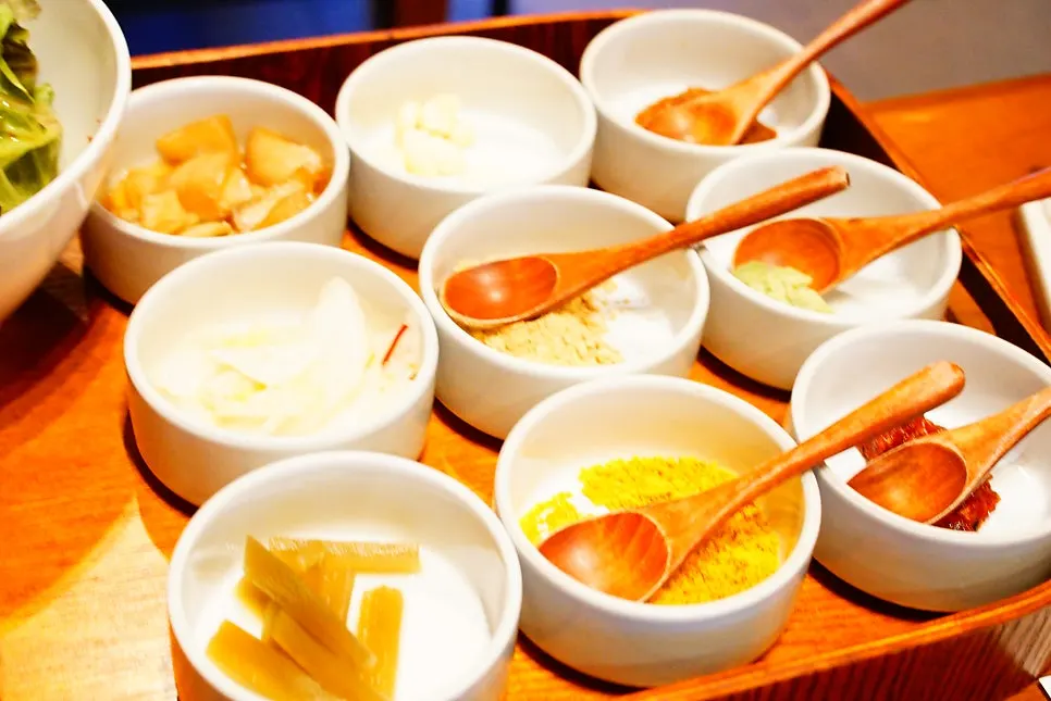Table spread of side sauces including whole garlic, wasabi, and soybean powder