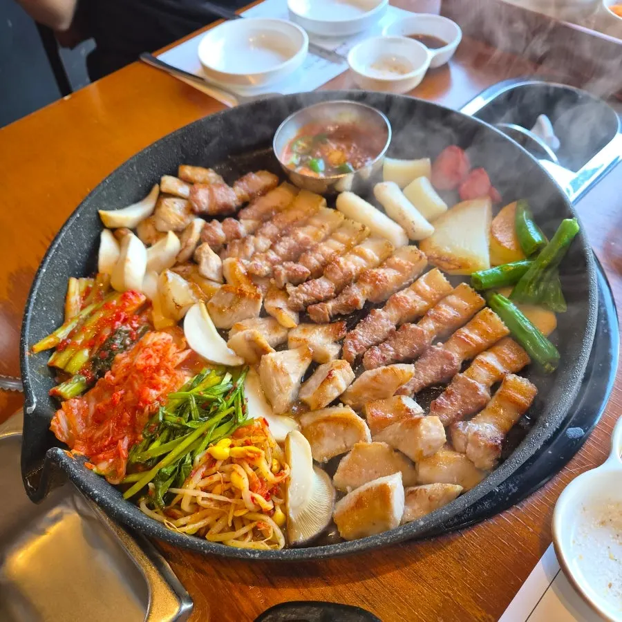Meat on the griddle with napa cabbage kimchi, green onion kimchi and bean sprout salad