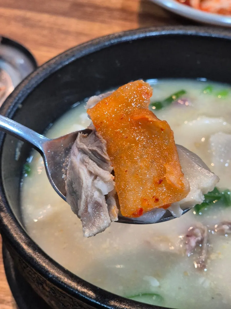 A spoonful of rice mixed with sundaeguk and kimchi on top