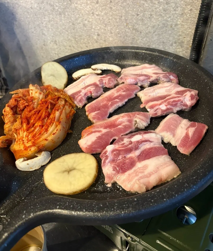 Pork belly on the grill with kimchi, mushrooms and potato