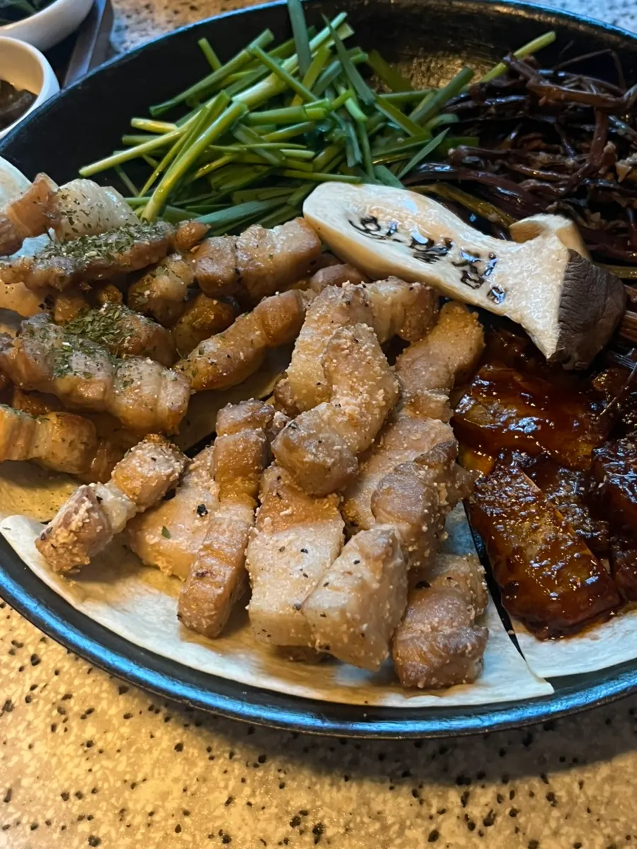 Wanbeoljip's meat platter topped with chives and bracken fern