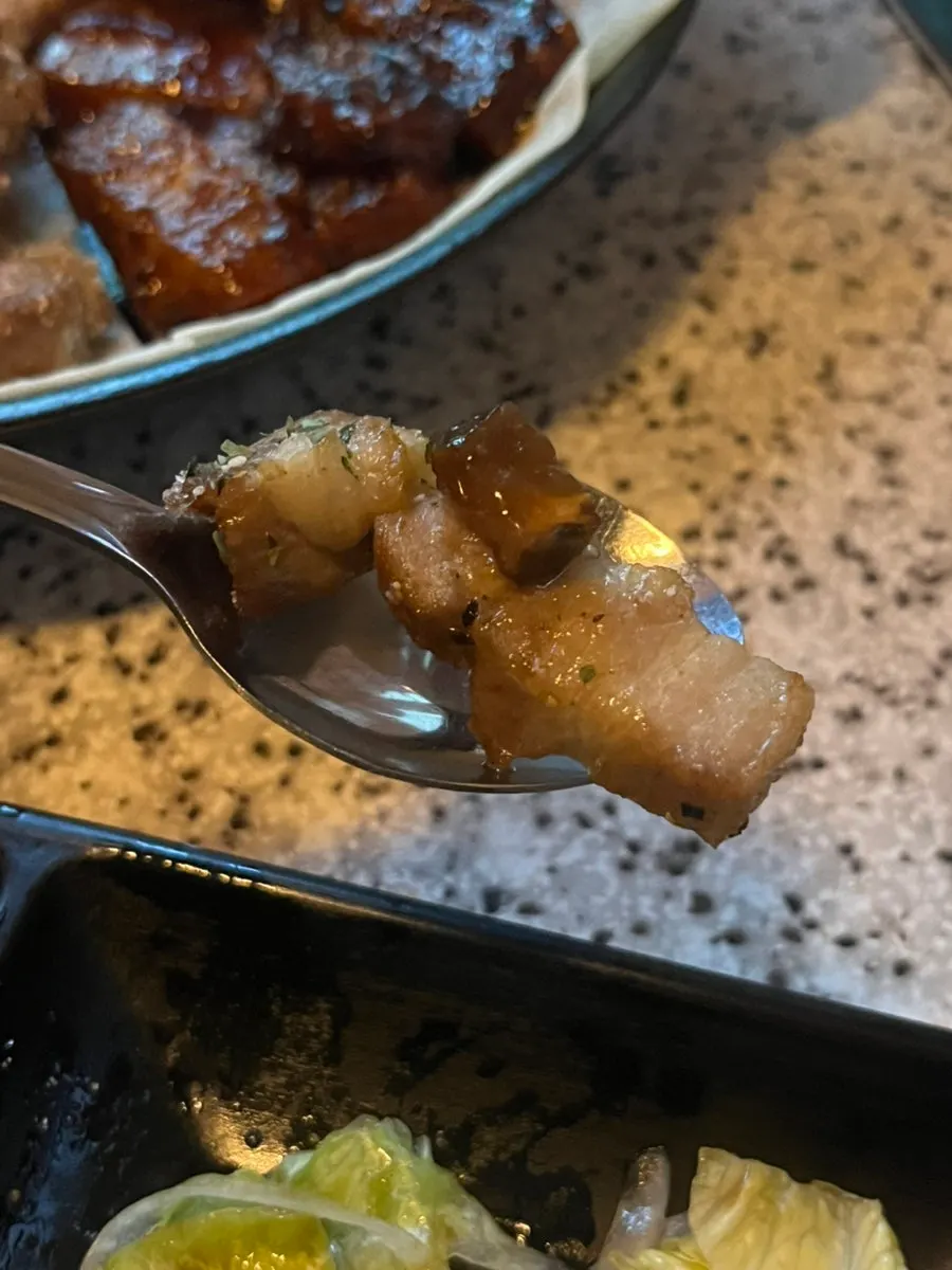 A bite of aged pork belly on top of dressed salad