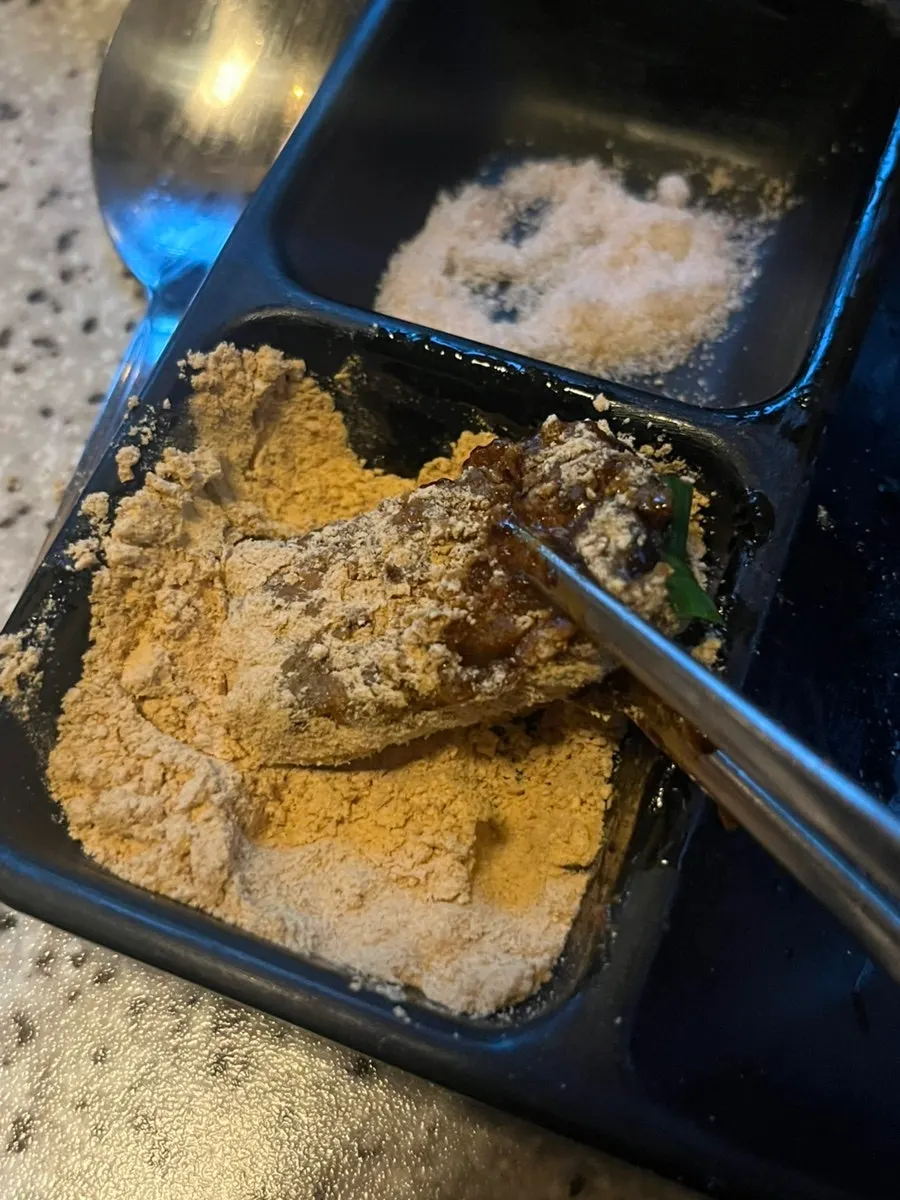 Sweet and spicy pork skin being coated in soybean powder