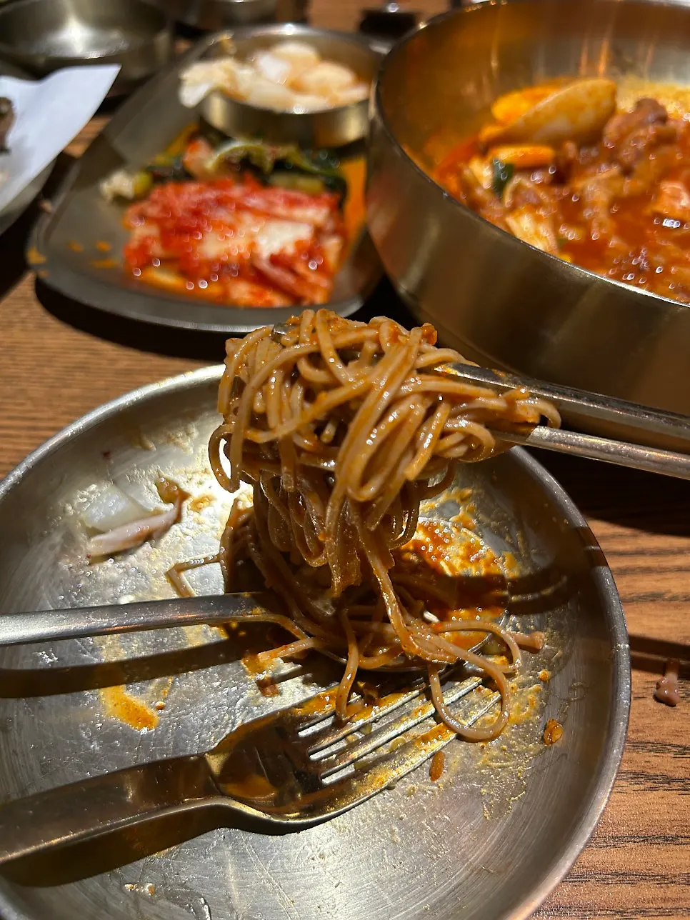 Chewy makguksu noodles lifted with chopsticks