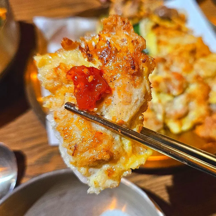 A piece of chicken jeon topped with salted relish