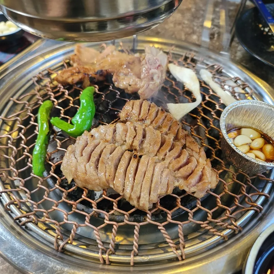Seasoned pork galbi cooking over the charcoal grill