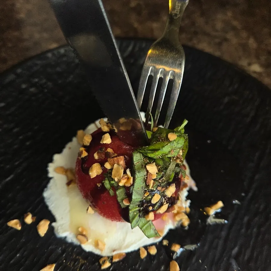 Whole tomato ricotta cheese salad topped with nuts and vegetables