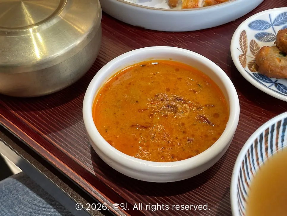 Side dishes of seasoned black beans, pickled radish, meat patties, and kkakdugi