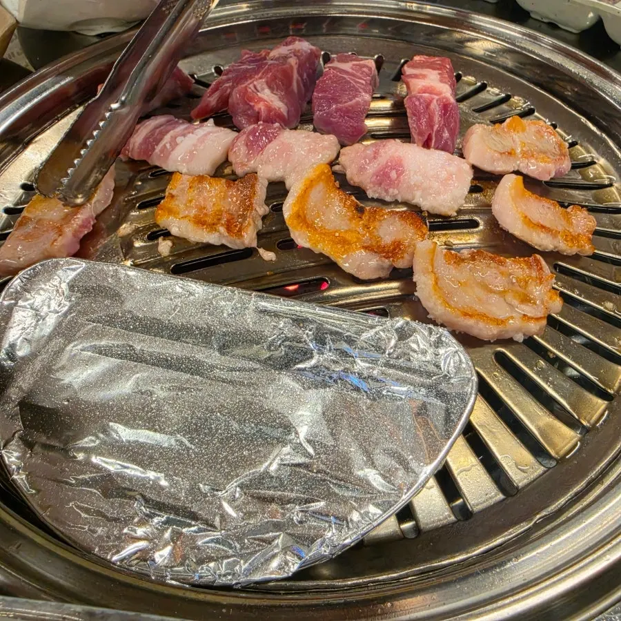 Pork belly grilling over charcoal