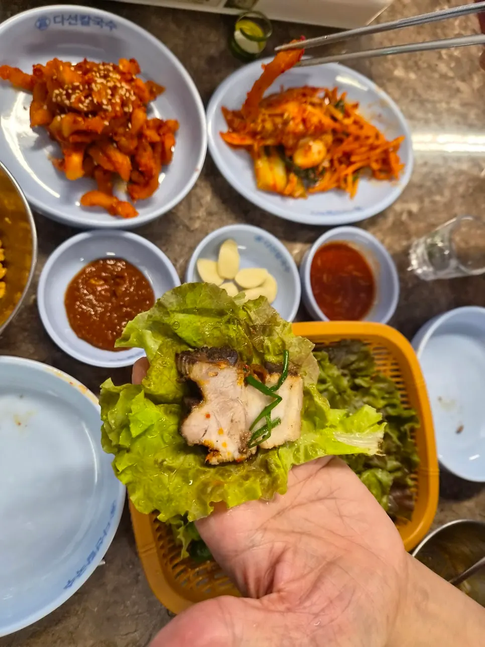 보쌈김치에 고기와 마늘을 올려 싸 먹는 모습