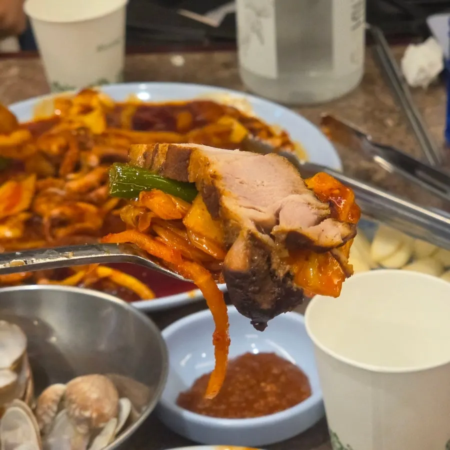 A bite of bossam served alongside radish salad