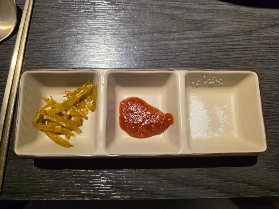Small dishes of pickled peppers, ssamjang, and salt