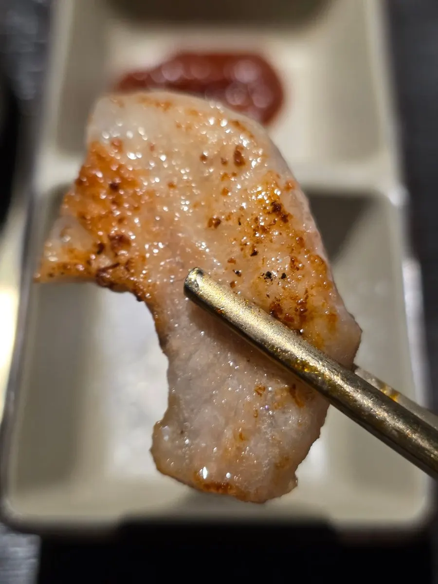 Duroc pork jowl grilling quickly on the cauldron lid