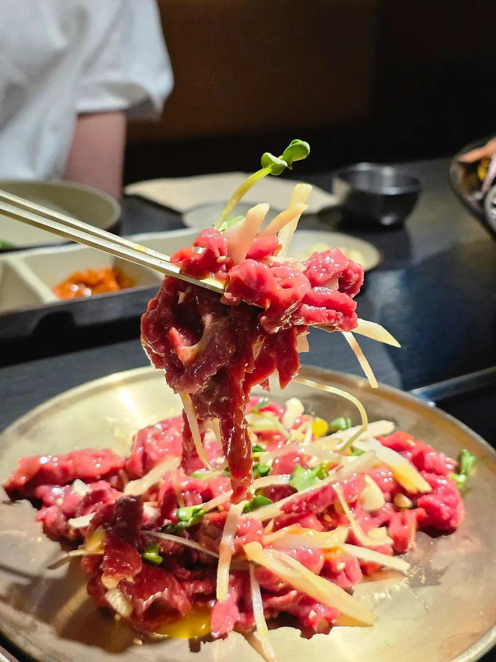 Yukhoe topped with sesame seeds and radish sprouts