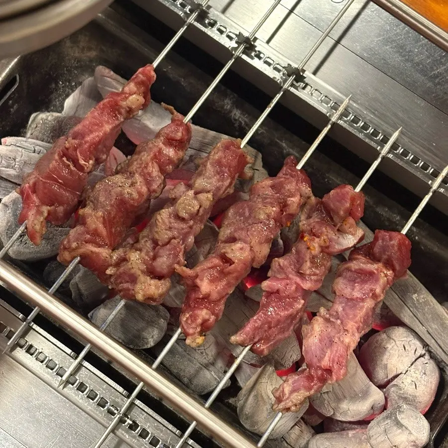 Skewers cooking over strong charcoal heat