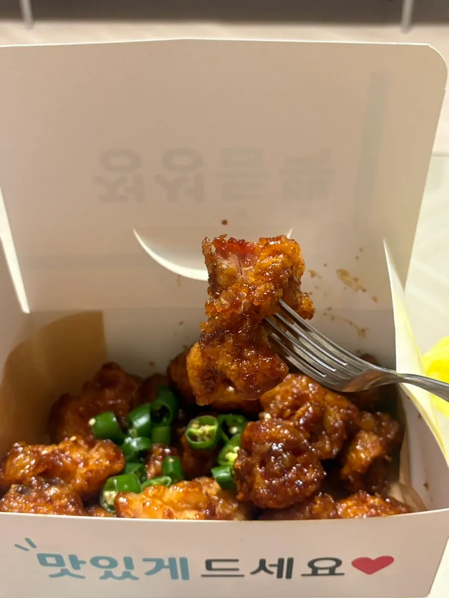 A piece of dakgangjeong showing the crispy batter