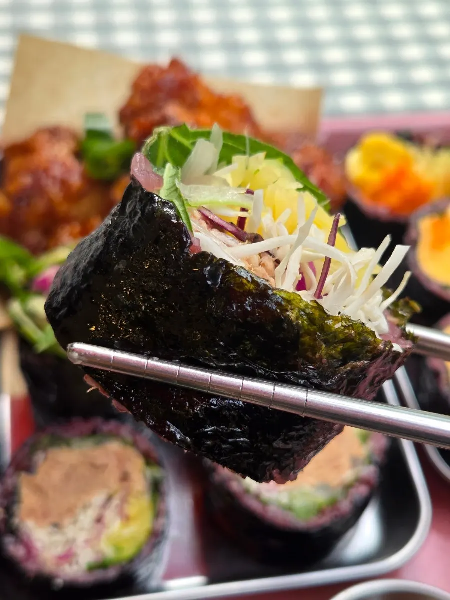 Tuna gimbap piece held with chopsticks