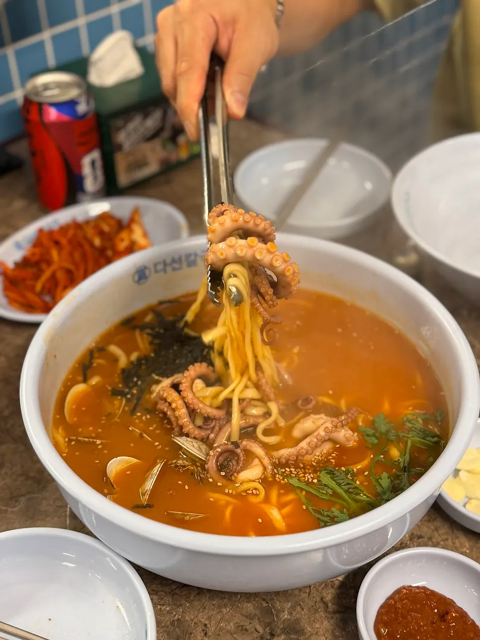 A full table with barley rice, boiled pork bossam, and spicy octopus kalguksu