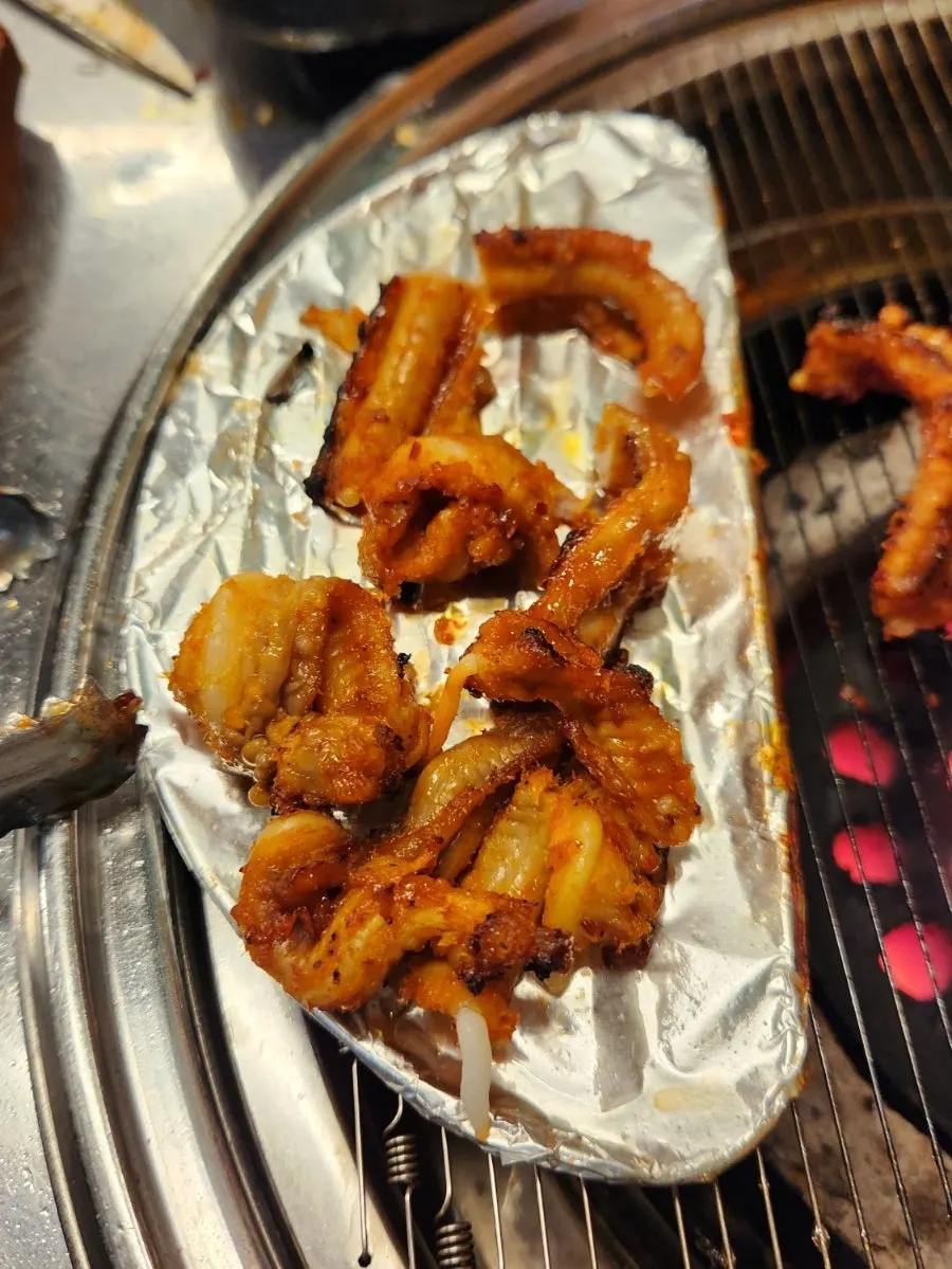 Seasoned kkomjangeo grilling on the charcoal wire rack