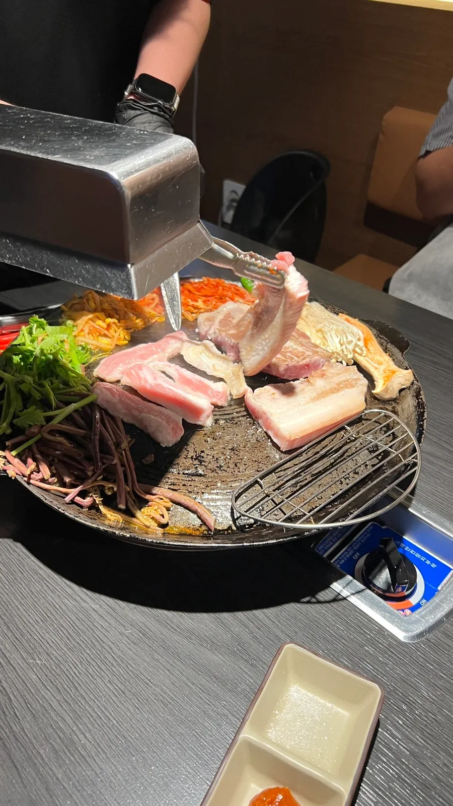 Meat placed on the cauldron lid with minari and enoki mushrooms