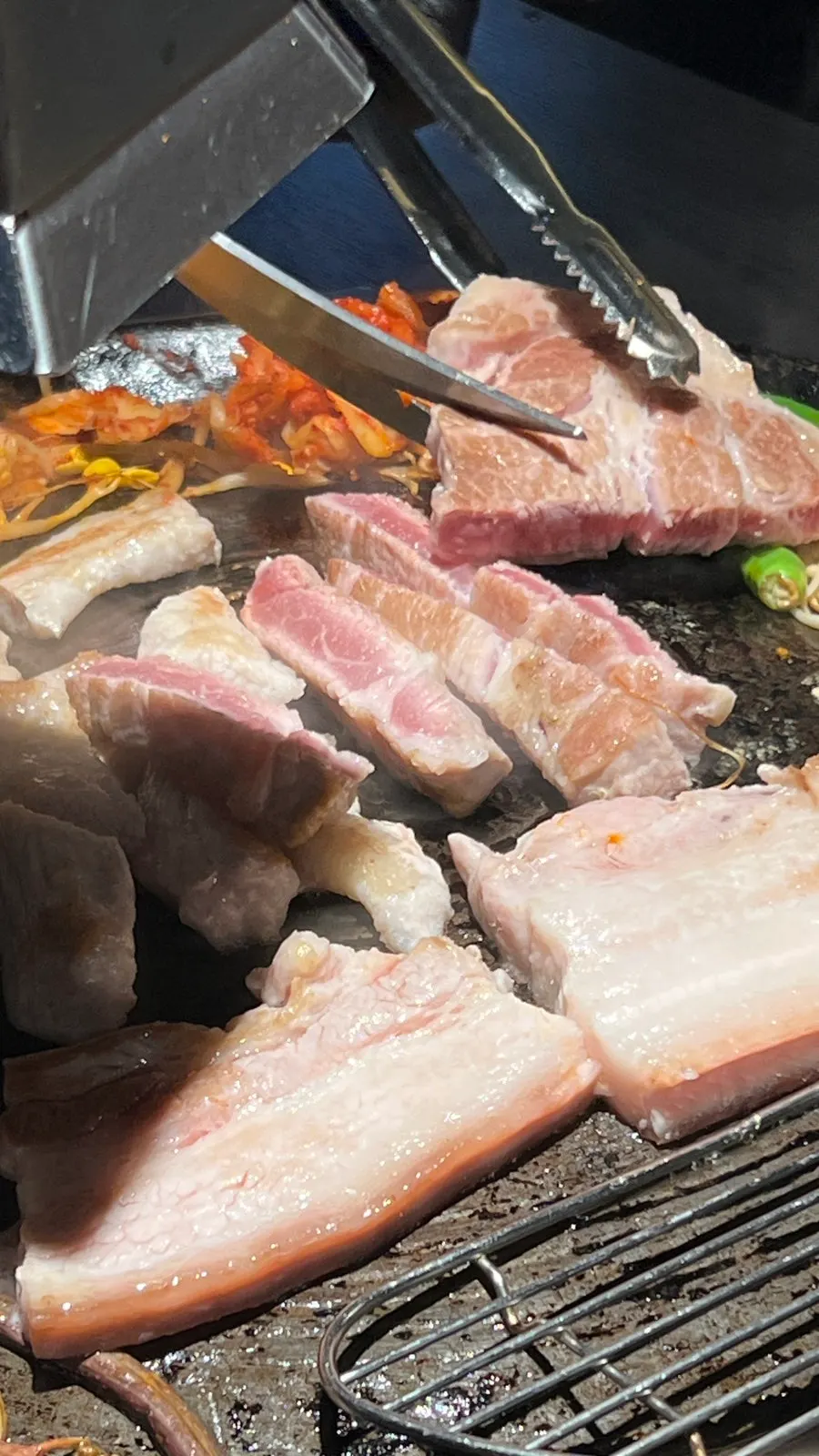 Staff member grilling meat on the cauldron lid
