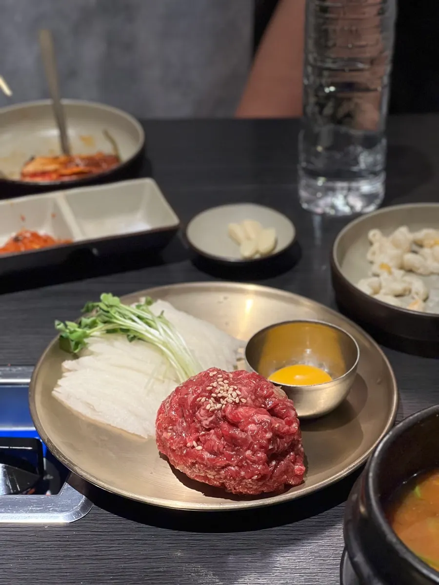 Minari and bean sprouts cooking at the edge of the cauldron lid