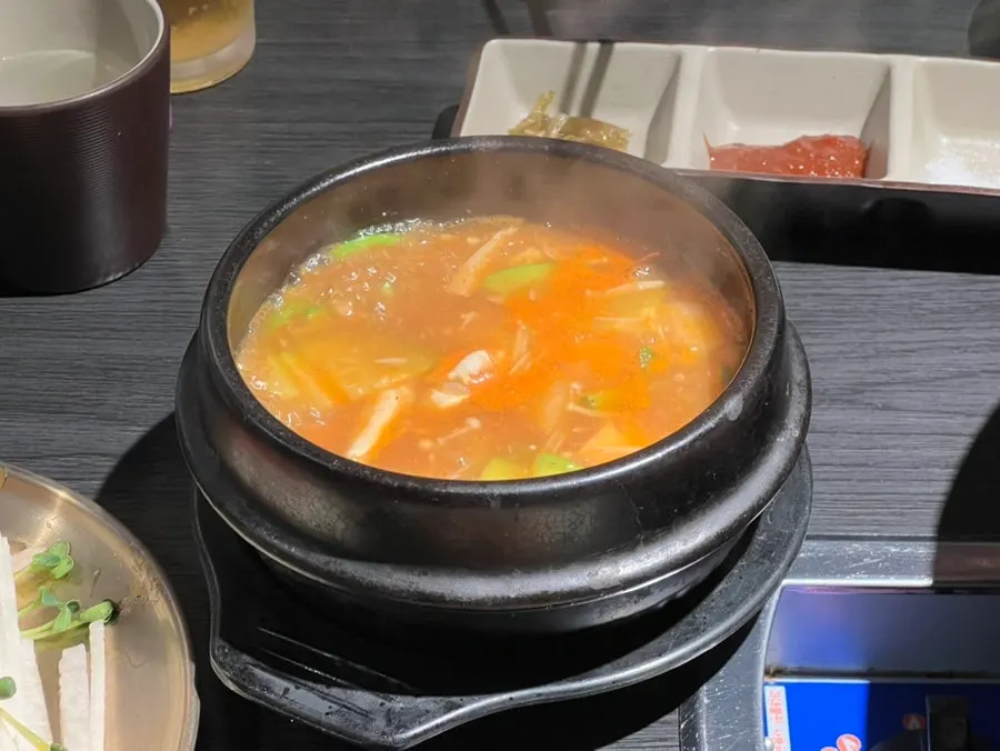 Crab miso stew simmering alongside side dishes