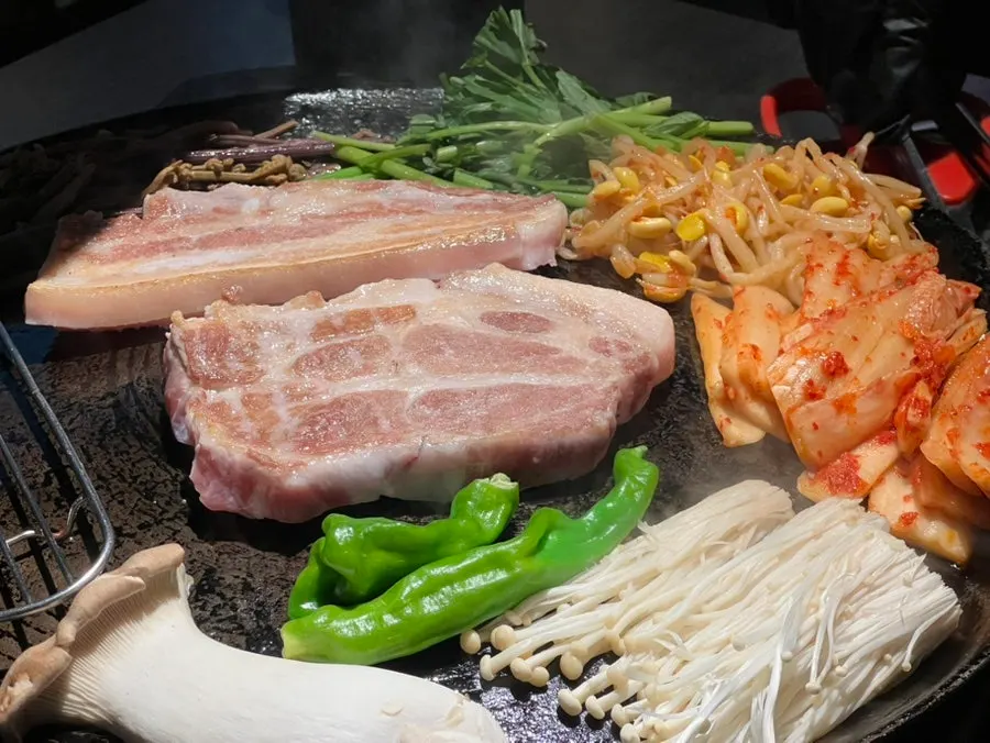 Pork belly and kimchi grilling on the cauldron lid