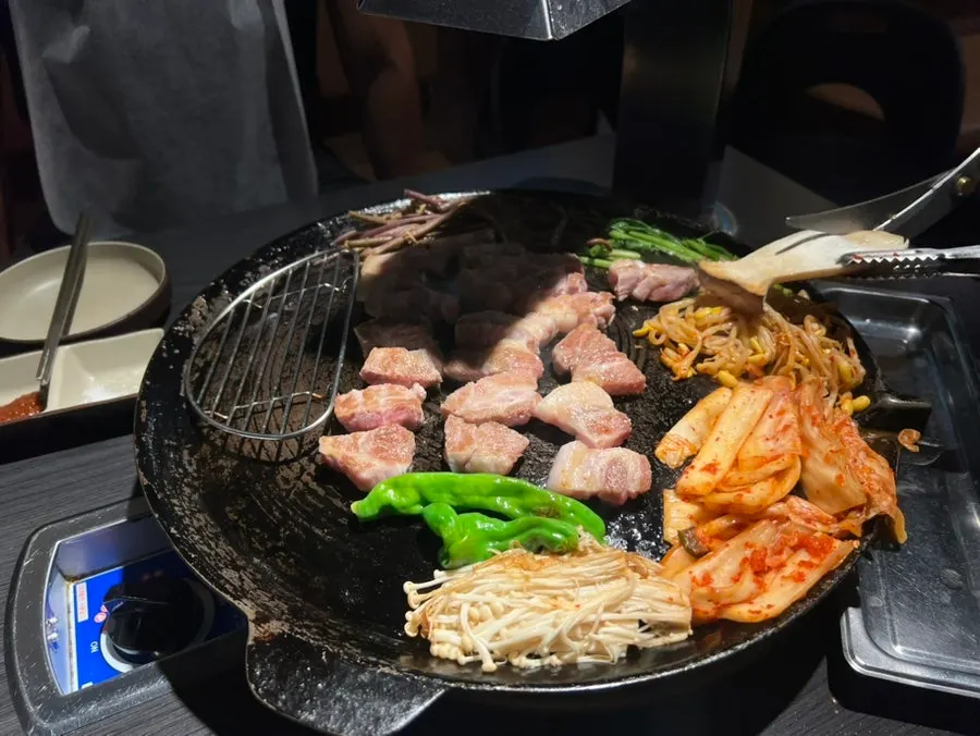 Staff member grilling meat on the cauldron lid with tongs